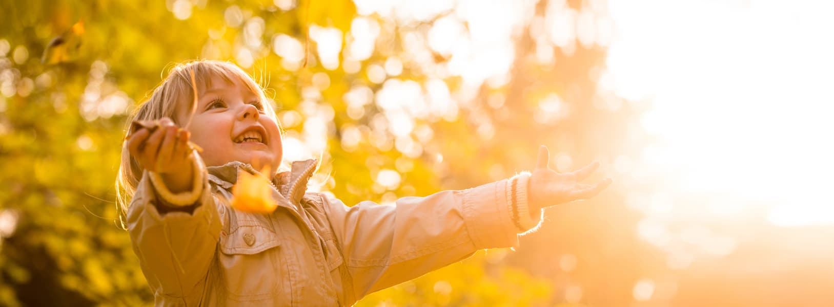 Child enjoying Autumn leaves falling