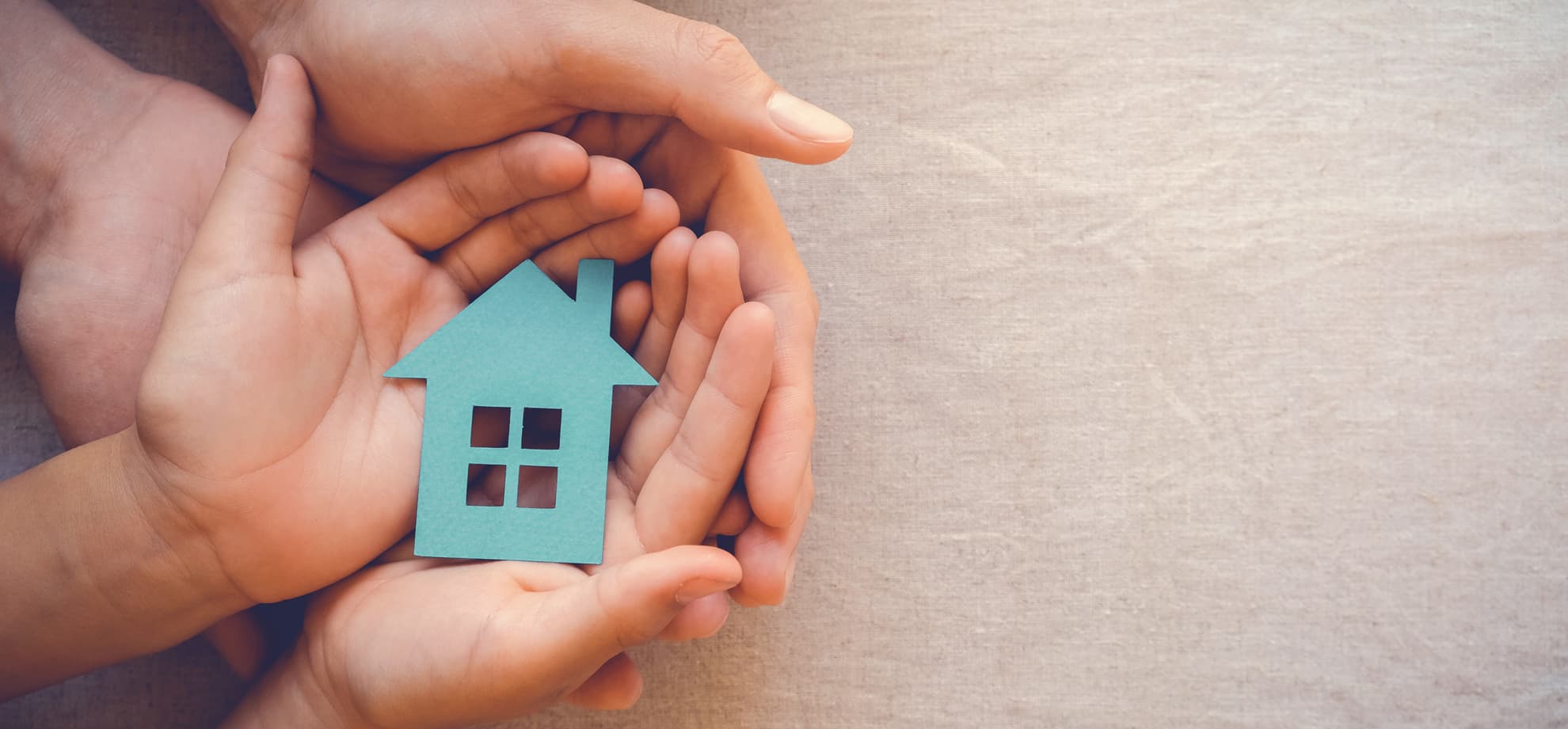 Parent and child’s hands holding paper cutout of a house